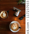 Denpasar, Bali, Saturday, 19 January 2019. Close-up photo of two cappuccino cups with sunglasses and a camera on a wooden table 117237033