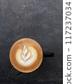 Close-up photo of a cappuccino with latte art in a ceramic cup on a concrete table. 117237034