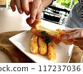 A single person sitting at a table enjoying a slice of fried mozzarella sticks. 117237036