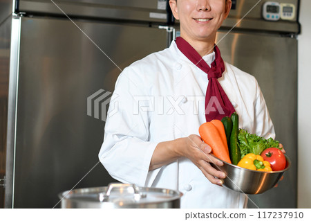Young asian male chef holding lots of vegetables 117237910