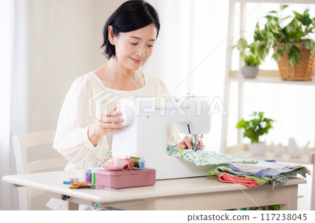 Hobby: Middle-aged woman sewing with a sewing machine Hobby: Middle-aged woman sewing with a sewing machine 117238045