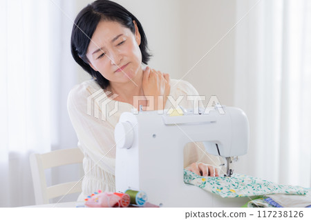 Sewing: Middle-aged woman suffering from stiff shoulders 117238126