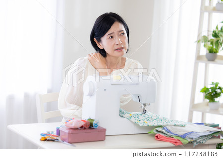 Sewing: Middle-aged woman suffering from stiff shoulders 117238183