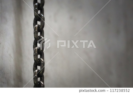 Chains hanging in a dimly lit room Chains hanging in a dimly lit room 117238552