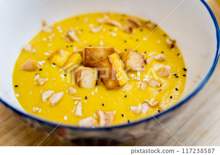 A bowl of pumpkin porridge with tofu and vegetables 117238587