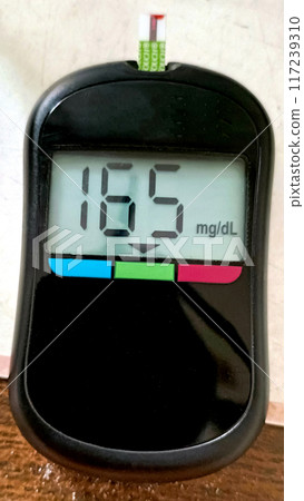 A close up of blood glucose meter with high sugar reading on wooden table A close up of blood glucose meter with high sugar reading on wooden table 117239310