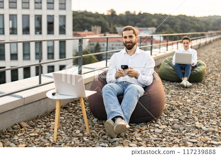 Two professionals working remotely on modern rooftop 117239888