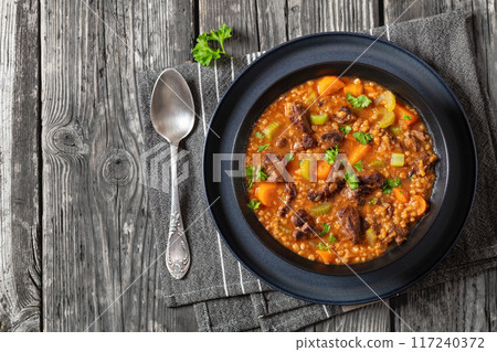 beef barley soup in a bowl, top view 117240372