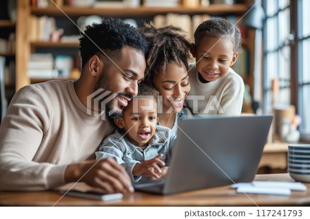 A loving family spending quality time together, gathered around a laptop at home, sharing joyful moments 117241793