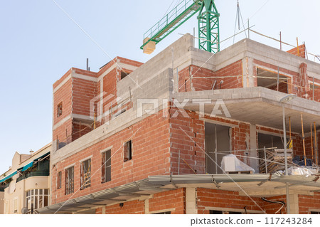 Close-up of an urban construction site with unfinished brick and concrete building under clear skies. Perfect for content related to urban development, architecture, and construction. Close-up of an urban construction site with unfinished brick and concrete building under clear skies. Perfect for content related to urban development, architecture, and construction. 117243284