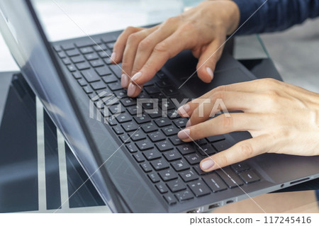 Close up shot of the woman with beautiful hands in the business attire, working on the laptop in the office, making notes 117245416