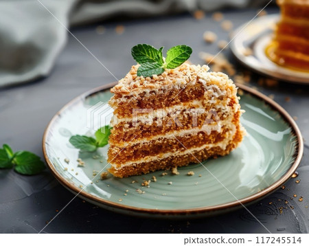 A slice of layered cake is presented on a plate, garnished with fresh mint, showcasing its rich texture and delightful filling. 117245514