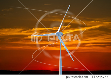 A wind turbine is spinning in the sky above a sunset 117245743