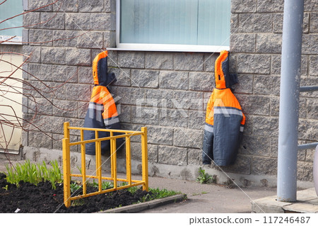 Two overalls hung under the window of a residential building, spring work in a flower garden Two overalls hung under the window of a residential building, spring work in a flower garden 117246487