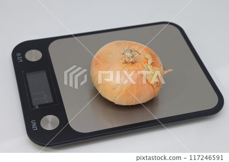 Golden flat onion on electronic kitchen scales. Proper nutrition. Calorie counting. Avitaminosis. Golden flat onion on electronic kitchen scales. Proper nutrition. Calorie counting. Avitaminosis. 117246591