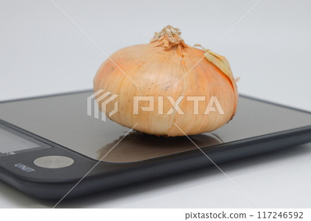 Golden flat onion on electronic kitchen scales. Proper nutrition. Calorie counting. Avitaminosis. Golden flat onion on electronic kitchen scales. Proper nutrition. Calorie counting. Avitaminosis. 117246592