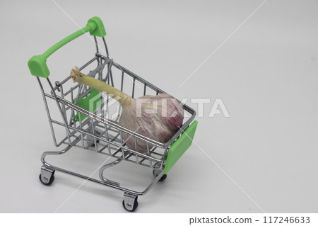 garlic in a toy grocery cart on a light background, proper nutrition. 117246633