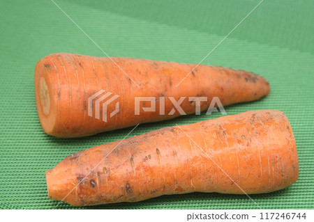 Poorly washed carrots lie on a green background, carrots deteriorate, proper nutrition. Poorly washed carrots lie on a green background, carrots deteriorate, proper nutrition. 117246744