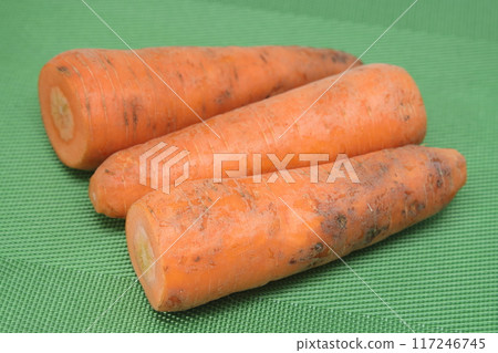 Poorly washed carrots lie on a green background, carrots deteriorate, proper nutrition. Poorly washed carrots lie on a green background, carrots deteriorate, proper nutrition. 117246745