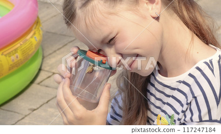 Teenager girl look at snail in box in nature. Discovery and exploring in summer. Teenager girl look at snail in box in nature. Discovery and exploring in summer. 117247184