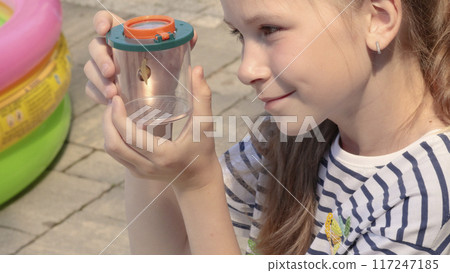 Teenager girl look at snail in box in nature. Discovery and exploring in summer.  117247185