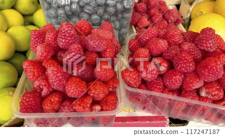 Raspberries and blueberries in containers. Foodstuffs and fruits. Harvest and market. Healthy eating. Raspberries and blueberries in containers. Foodstuffs and fruits. Harvest and market. Healthy eating. 117247187