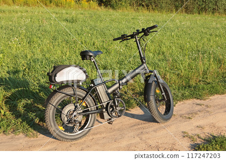 Electric folding bicycle for riding in nature in countryside. Sport and health. Summer hobby. Electric folding bicycle for riding in nature in countryside. Sport and health. Summer hobby. 117247203
