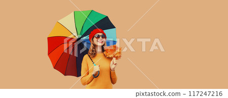 Autumn stylish cheerful young woman holds yellow maple leaves with colorful umbrella yellow sweater 117247216