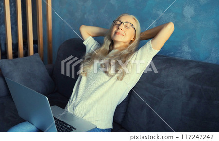 Happy mature woman relaxes working on laptop, female freelancer enjoys free time sitting at home Happy mature woman relaxes working on laptop, female freelancer enjoys free time sitting at home 117247242