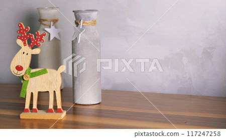 Decorative Christmas composition. Wooden reindeer and Christmas tree, vases with stars. Festive mood for living room. Template for postcard. Decorative Christmas composition. Wooden reindeer and Christmas tree, vases with stars. Festive mood for living room. Template for postcard. 117247258
