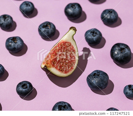 Layout of fresh blueberries and a slice of figs on a purple background close up. Layout of fresh blueberries and a slice of figs on a purple background close up. 117247521