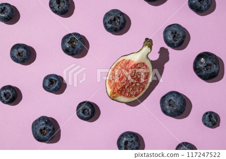 Layout of fresh blueberries and a slice of figs on a purple background. Layout of fresh blueberries and a slice of figs on a purple background. 117247522