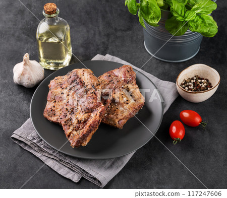 Grilled bbq lamb ribs with tomato and fresh herb on a plate on a  dark background. 117247606