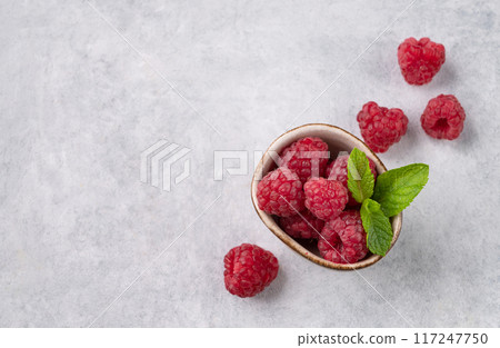 Juicy forest raspberry with mint leaf i a bowl on a light textured background. Healthy food concept 117247750