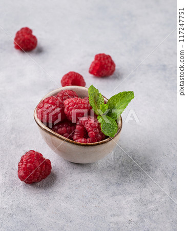 Juicy forest raspberry with mint leaf i a bowl on a light textured background. Healthy food concept. 117247751