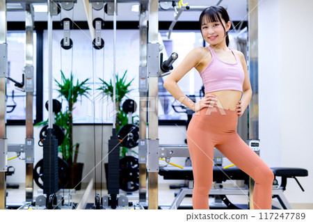微笑的年輕女性在健身房、飲食、私人健身房、肌肉訓練女孩、緊身褲中擺姿勢 117247789