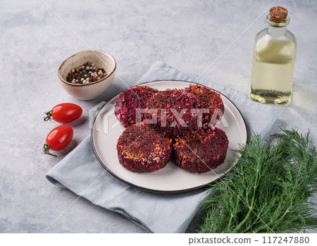 Fried vegetarian cutlets from beet, on a plate on a light background with fresh herbs and tomatoes 117247880