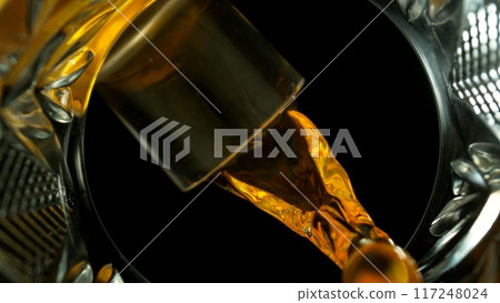 Freeze Motion Shot of Whiskey Liquid Pouring, Macro, Unique Angle of View from the Bottom of the Glass Freeze Motion Shot of Whiskey Liquid Pouring, Macro, Unique Angle of View from the Bottom of the Glass 117248024