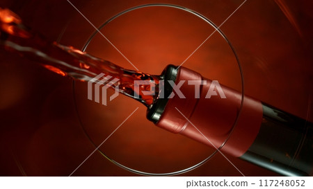 Freeze Motion Shot of Red Wine Pouring, Unique Angle of View from the Bottom of the Glass 117248052