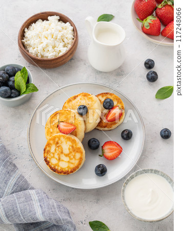 Pancakes with cottage cheese with fresh blerries and sour cream on a gray background. Pancakes with cottage cheese with fresh blerries and sour cream on a gray background. 117248066