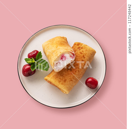 Delicious homemade pancakes or crepes with cottage cheese and fresh cherries on a pink background. Delicious homemade pancakes or crepes with cottage cheese and fresh cherries on a pink background. 117248442