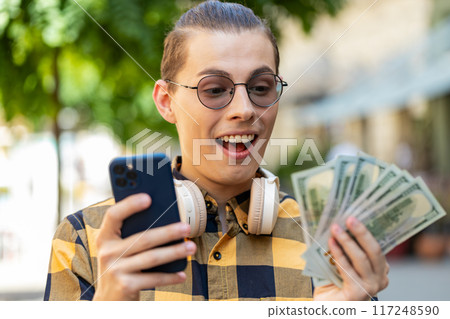 Happy rich man counting holding money dollar cash use smartphone mobile calculator app online order Happy rich man counting holding money dollar cash use smartphone mobile calculator app online order 117248590