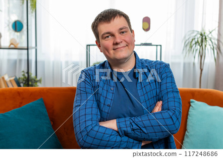 Portrait of happy Caucasian man sitting on couch looking at camera and smiling relaxing at home 117248686