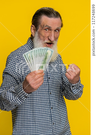 Rich happy senior man winner waving money dollar cash like a fan, big income wealth success business 117248699