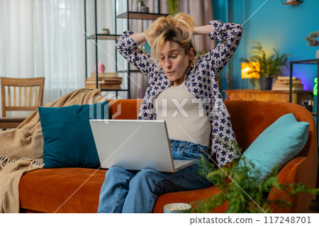 Happy woman using laptop receive good news shocked by victory celebrate lottery jackpot win at home Happy woman using laptop receive good news shocked by victory celebrate lottery jackpot win at home 117248701