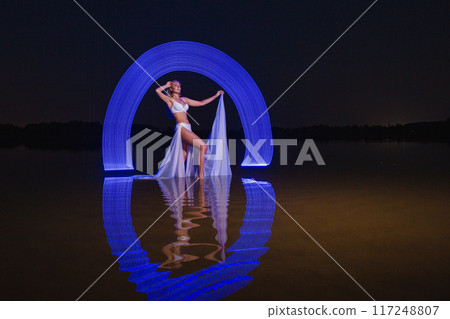 Young slim girl posing in water with abstract blue light effect 117248807