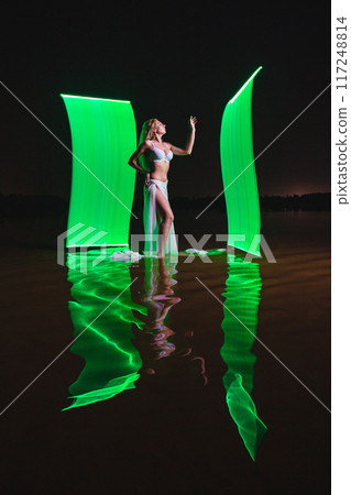 Young slim girl posing in water with abstract green light effect Young slim girl posing in water with abstract green light effect 117248814