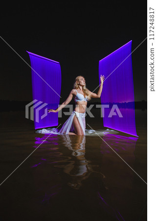 Young slim girl posing in water with abstract purple light effect 117248817