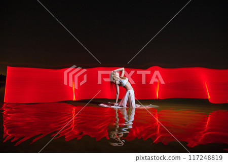 Young slim girl posing in water with abstract red light effect Young slim girl posing in water with abstract red light effect 117248819