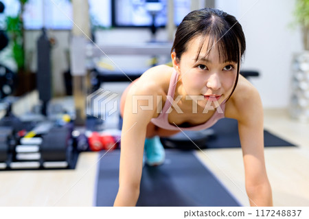 Young woman training her body at a personal gym, muscle training girl, push-ups, plank 117248837